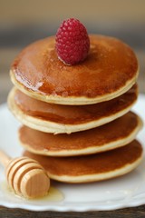Delicious pancakes with raspberries and honey in a bowl 