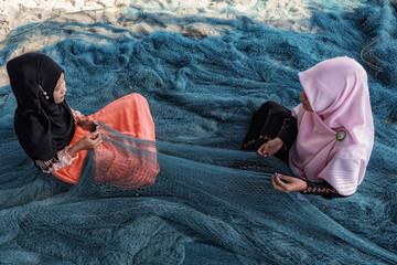 muslim girl - fishermen are repairing fishing nets.Fishermen are cleaning fishing - 174533327