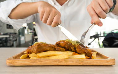 A man wearing white shirt eating steak and french fries in restaurant