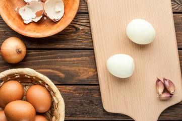 boiled chicken eggs at cutting board decorated with food ingredients on wooden table