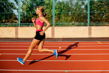 Side view beautiful young woman exercise jogging and running on athletic track on stadium