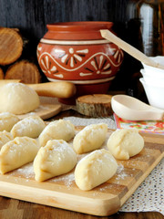 Fototapeta na wymiar Raw vareniki (Ukrainian cuisine meal) prepared for cooking are lying on a chopping board sprinkled with flour