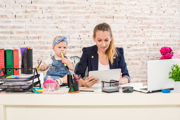 Mom and businesswoman working with laptop computer at home and playing with her baby girl.