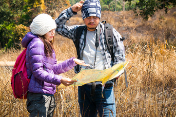 Asian travelers holding map and find target in forest