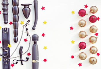 Various sex toys and Christmas decorations on a light background with red and yellow stars. Image for the festive season, for sales and discounts in sex shops. There is a free space for text