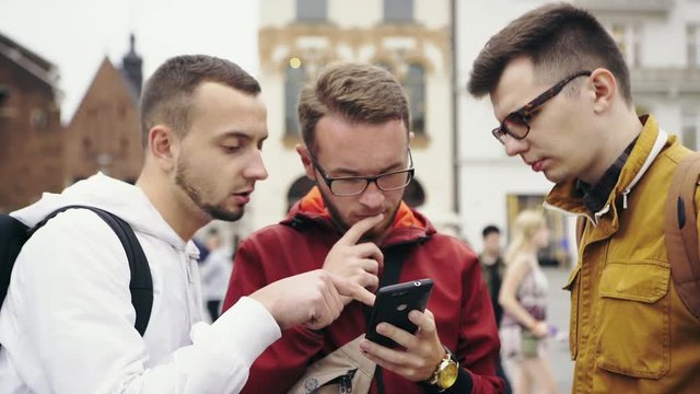 Three men discussing over city map in smartphone