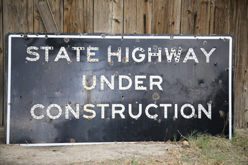 An old porcelain sign reading state highway under construction 