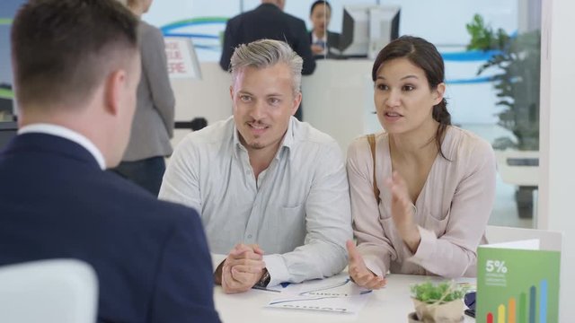  Modern city bank, couple talking to adviser & signing document