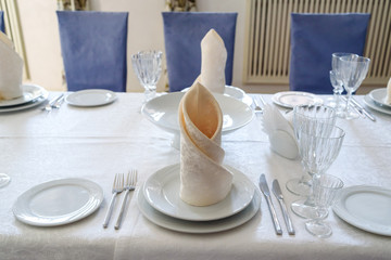 Table with white plate, crystal wineglasses, linen beige napkin and cutlery on tablecloths, free space for text. Elegant table setting for wedding banquet. Table service. Dinner place setting