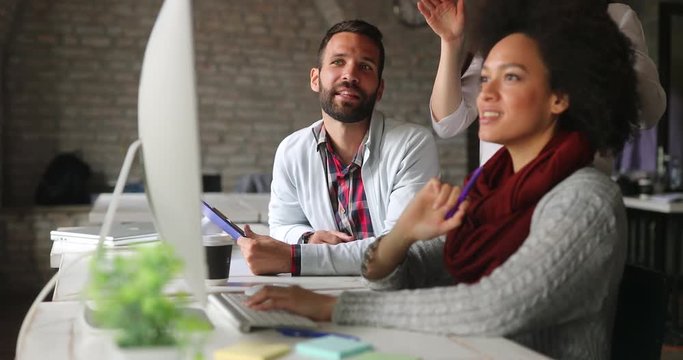 Group of young employees in office talking and working