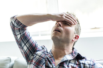 Young man suffering from headache at home