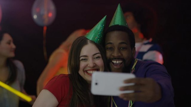  Nerdy friends having fun at house party pose to take a selfie with smartphone
