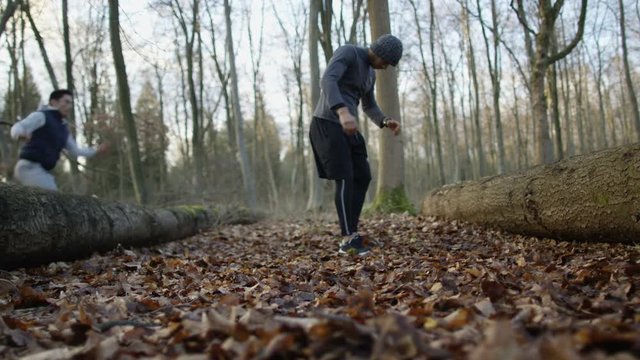 Group of runners running in forest, man stops to get his breath back.