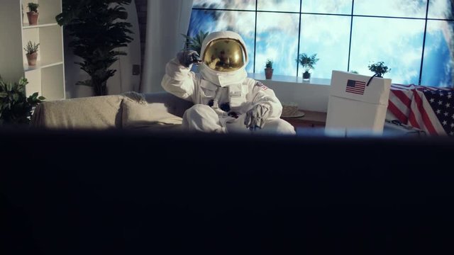  Astronaut relaxing in apartment, watching TV & drinking a beer