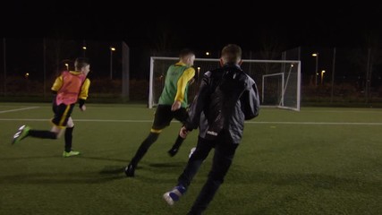 British youth soccer team train on floodlit pitch at night
