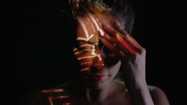  Light projected onto woman's face indicating brain activity or migraine