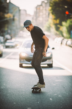 Pro skateboard rider in front of car on city street