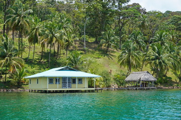 Tropical coastal landscape house and hut over the water with coconut trees on the land, Caribbean coast of Panama, Bocas del Toro, Central America