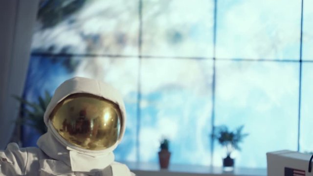  Astronaut in full suit relaxing in apartment, watching TV & channel surfing