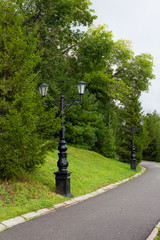 Street lamp in the old style with two lamps of wrought iron with curls on the long leg Black lamppost and chandelier body, light glass of plafonds