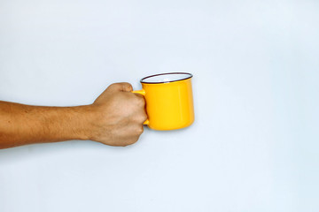 Yellow metal mug in the male hand on white background