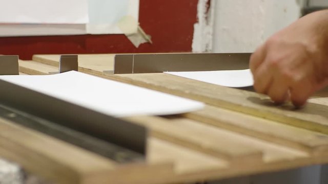 Manual folding of paper by a white man in a printing house