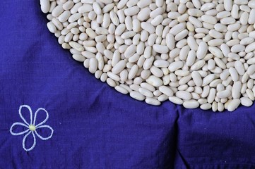 A lot of white dry beans on a blue background. The background image of delicious and healthy food.