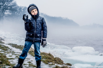 The boy walks in the misty weather near the river