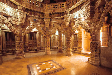 Columns with stone reliefs in Indian temple wall. Ancient architecture example with Jain motifs, Jaisalmer of India.