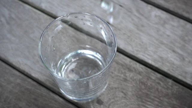 pouring water into glass on wood deck in 10x slow motion