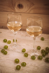 Two glasses of white wine and grapes on wooden table