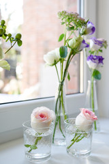 Fresh tender pink garden roses in glass vases on window sill. Beautiful flowers in wedding day. Wedding decoration, free space