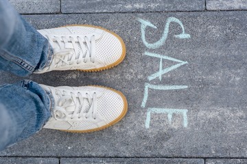 Sale ahead concept with woman feet on asphalt road with text