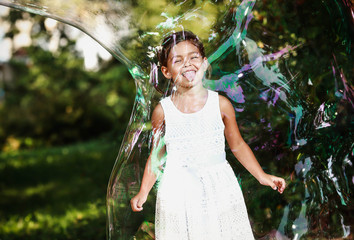 Маленькая девочка в гигантском мыльном пузыре - obrazy, fototapety, plakaty