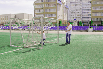Dad walks with his sons playing football.