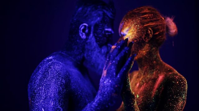 A man and a woman in the ultraviolet light caress each other. Fire and ice, two hypostases.