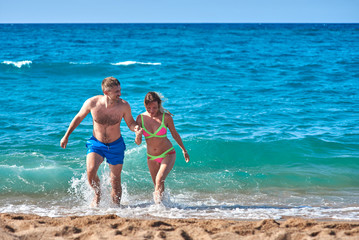 Caucasian man and woman getting out from the sea water. Front view.