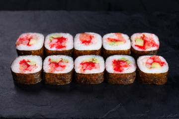 Japanese food, sushi restaurant. Delicious futomaki sushi rolls with caviar, salmon and scallop served on black slate with free space for text design
