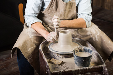 pottery, workshop tools, ceramics art concept - man hands work with potter's wheel, the fingers form the shape of raw fireclay, male master sculpt a utensils with stack, profile and sponge, top view