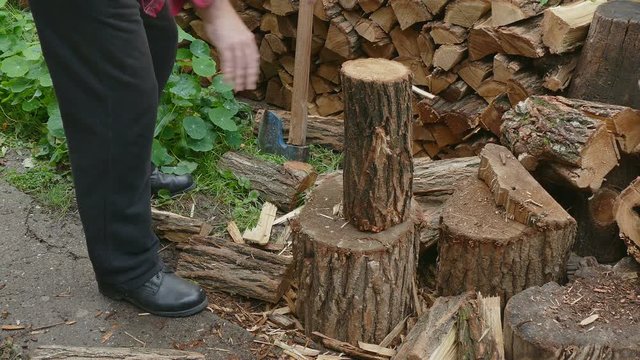 Lumberjack chopping firewood using axe, logs splitting
