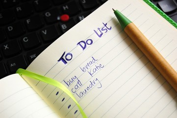 to do list hand written with a pen and computer in the background - 174589162