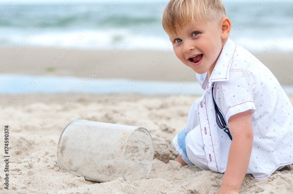 Wall mural Boy playing with sand on a beach