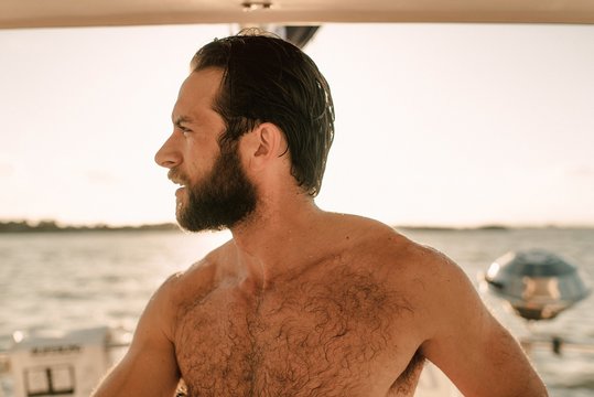 A shirtless man on a sailboat