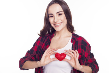 Young brunette girl holds a toy heart on a white background