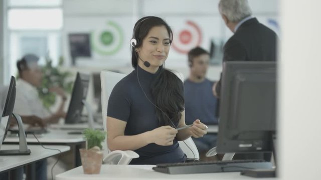  Customer service ops taking calls in busy call center with manager overseeing