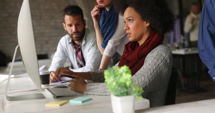 Group of young employees in office talking and working