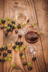 Red and white wine glasses and grape on wooden table