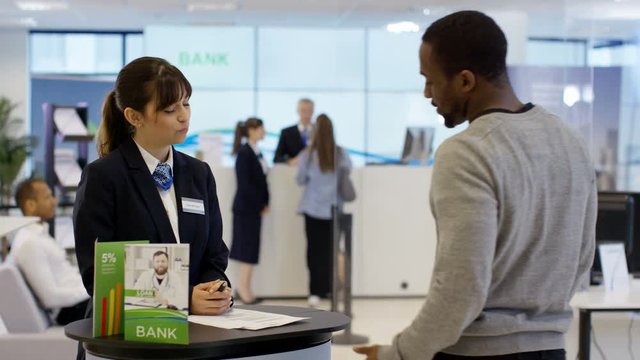  Bank worker on information desk giving help & advice to customers