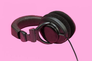 Stereo headphones in hand. On pink background