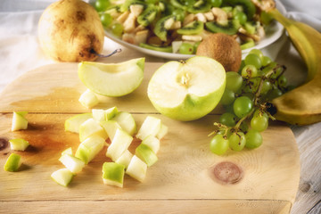 Ingredients for fruit salad. Cutting apple